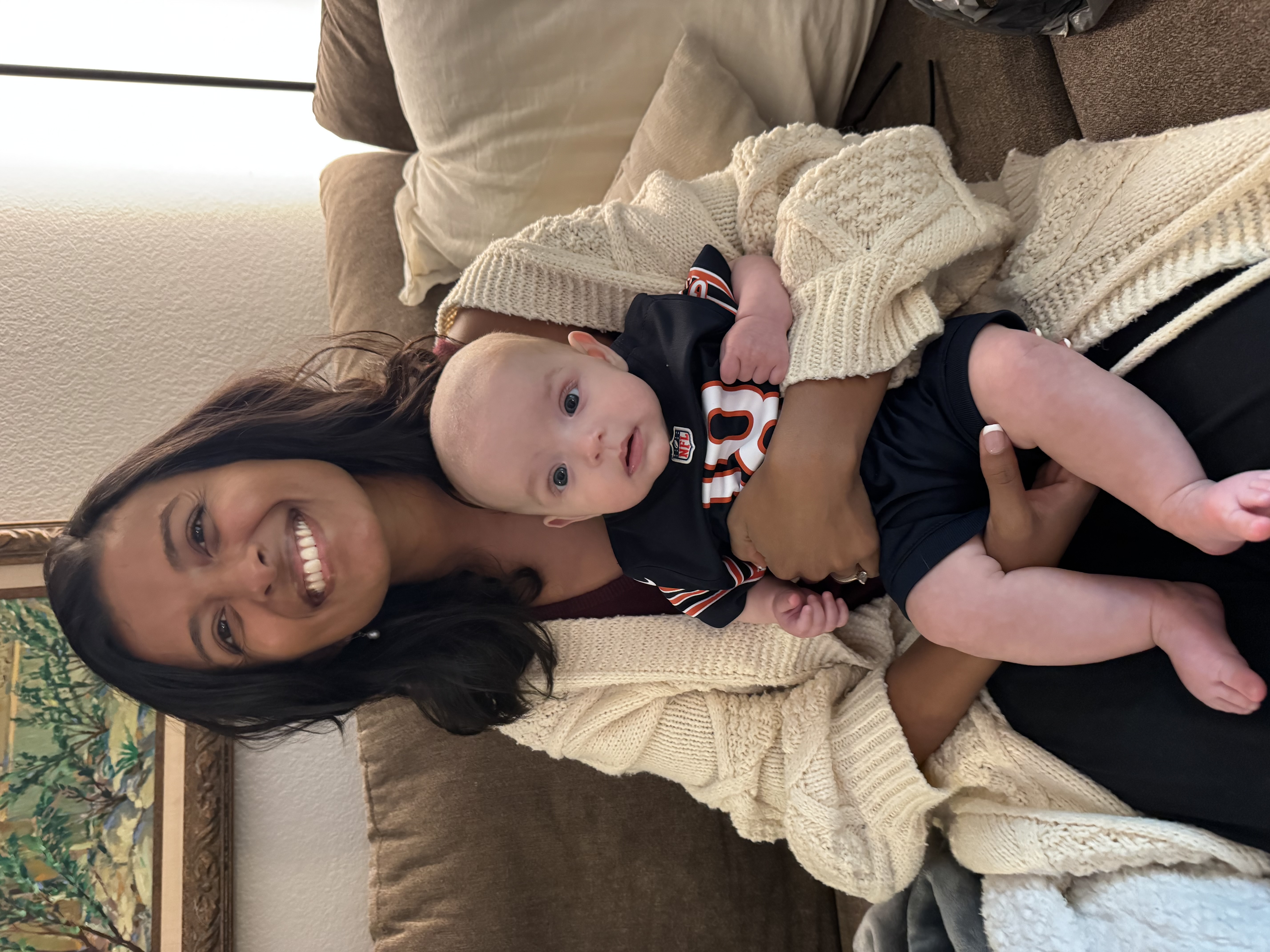 Dr. Priyanka Villanassery smiling, sitting upright with her baby